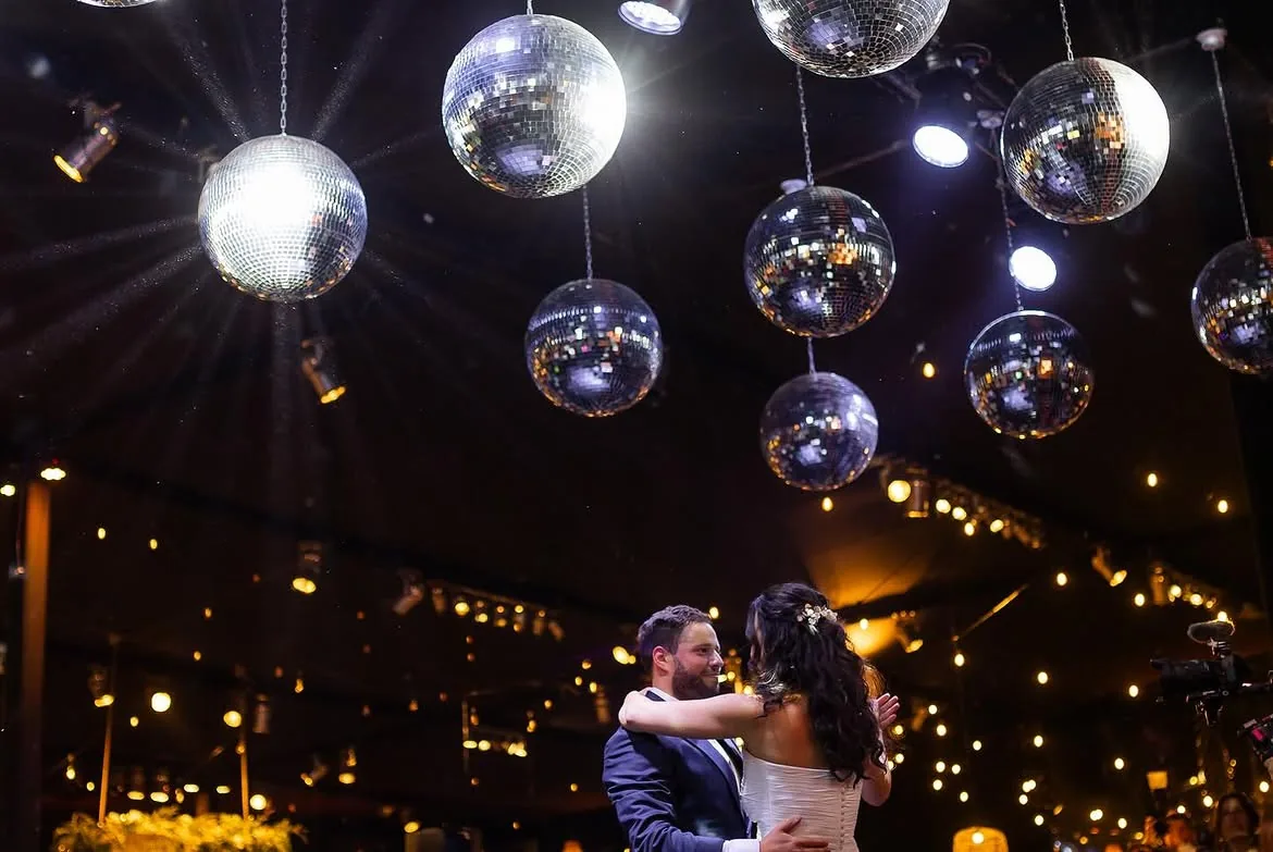 Novios abrazados bajo esferas disco doradas