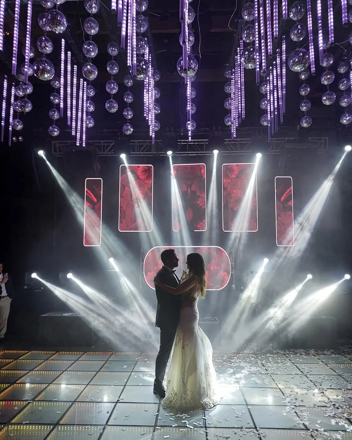 Primer baile de los novios bajo esferas disco e iluminación de pista
